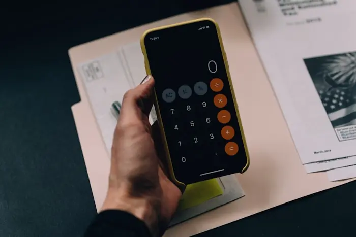 Calculating figures on a phone calculator over mortgage paperwork